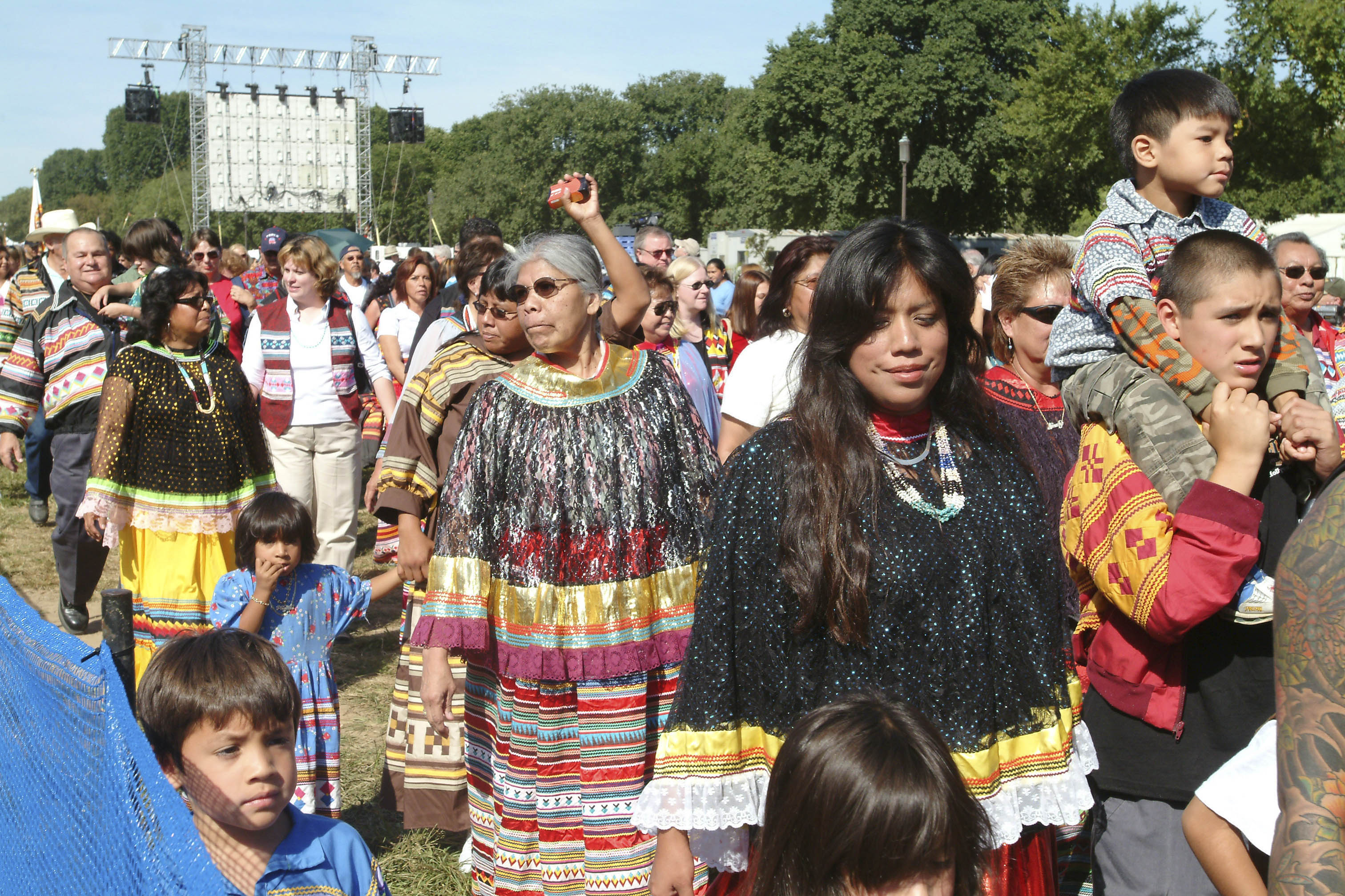 Grand opening of the National Museum of the American Indian: Native Nations Procession, September 21, 2004, by Donna M. Greene, Smithsonian Institution Archives, Acc. 11-009, Image no. 2004-54073. Women and children in colorful dresses walk in a crowd on the National Mall.