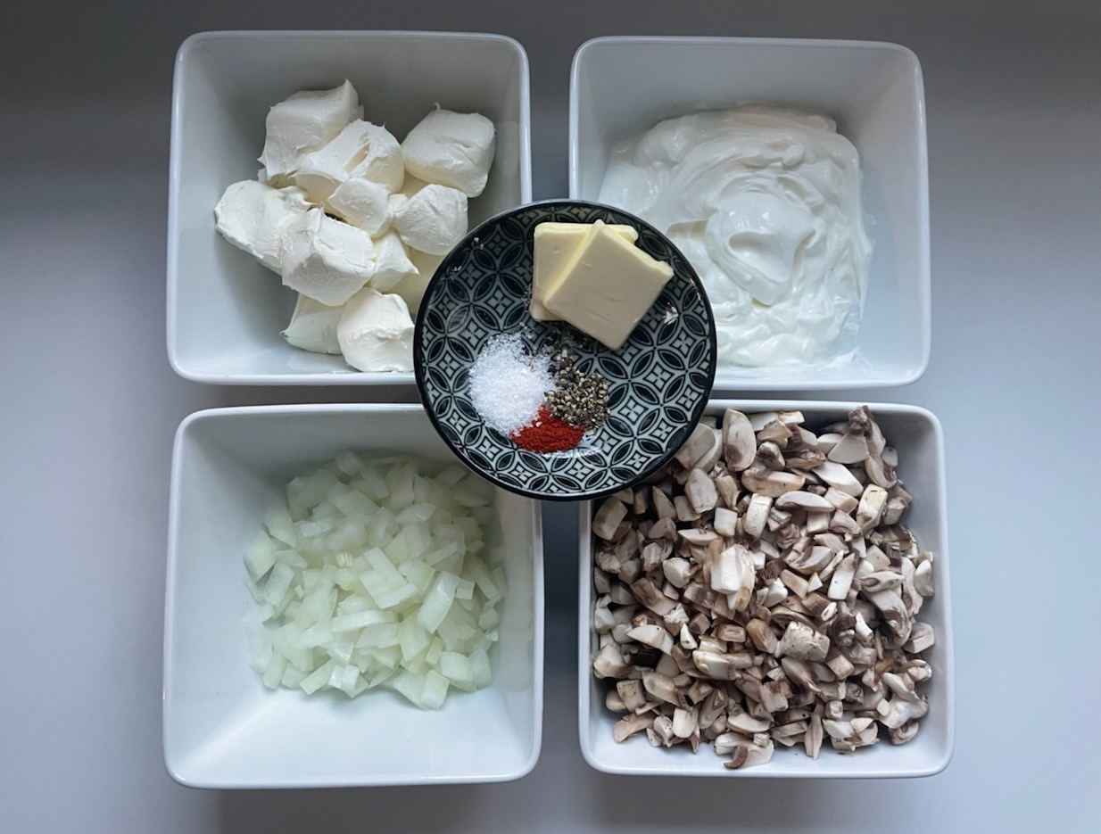 Ingredients for docent Rose Greenfield’s “Baked Mushroom Cheese Dip” from The NMNH Docent Cookbook (1984). Four square white bowls. They contain sour cream, cream cheese, diced mushrooms, and diced onions. There are slices of butter and little piles of salt, pepper, and cayenne.