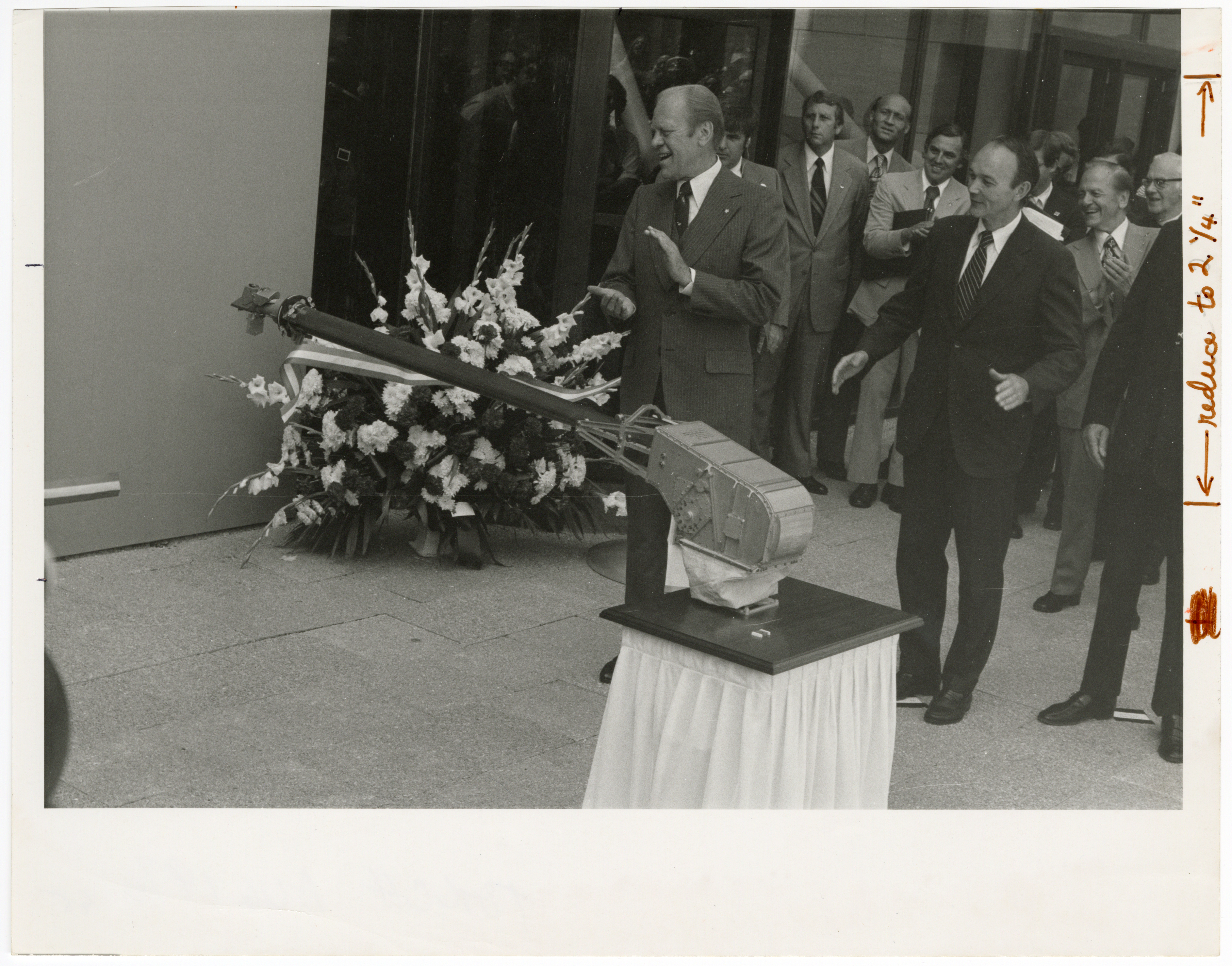 Opening Ceremony for National Air and Space Museum, 1976, by Richard Farrar. Smithsonian Institution Archives, Record Unit 371, Image no. 76-8428-15. Men in suits stand outside of the entrance of the National Air and Space Museum. A replica of the mechanical arm of the Viking lander is also pictured.