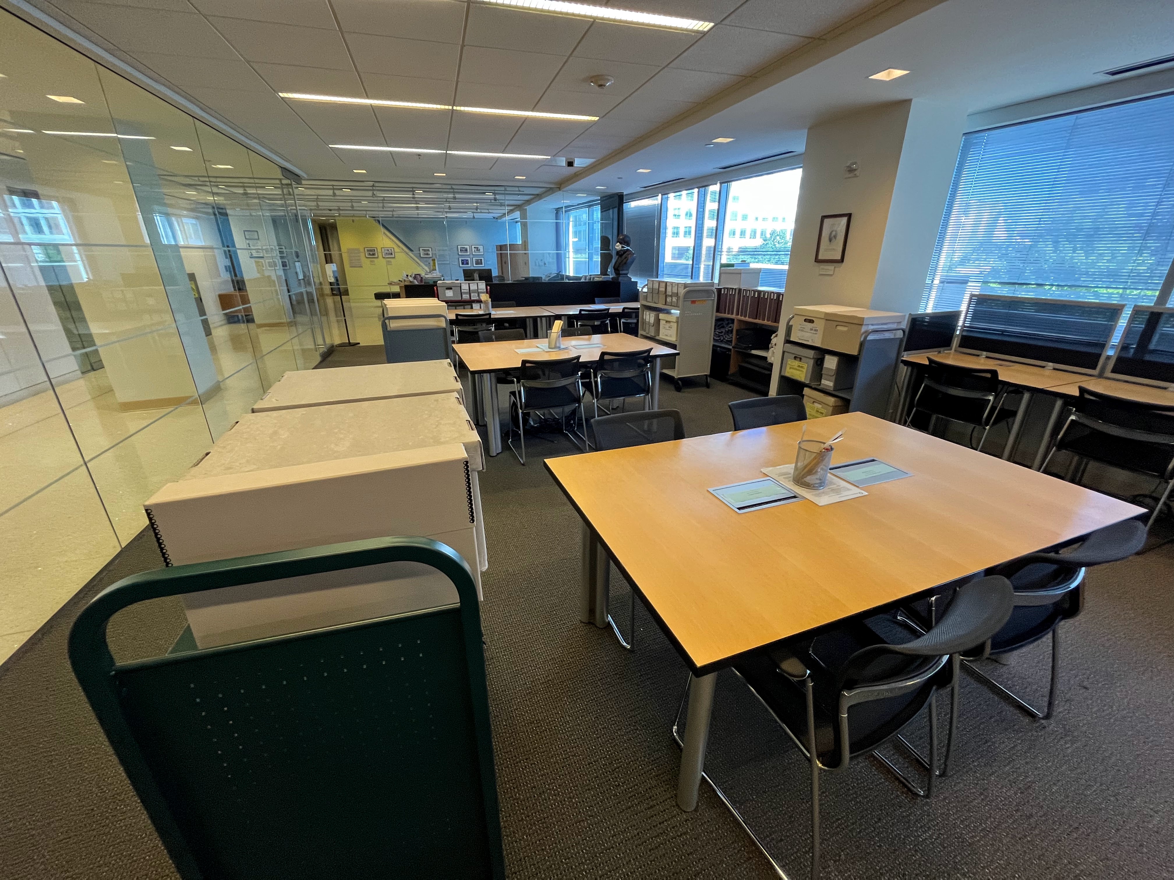 Before the reading room opens, carts piled high with archival materials await their users. Photo by Deborah Shapiro. View of the reading room from the view of reference book shelves. Carts with archival boxes sit on carts next to tables in the empty room.