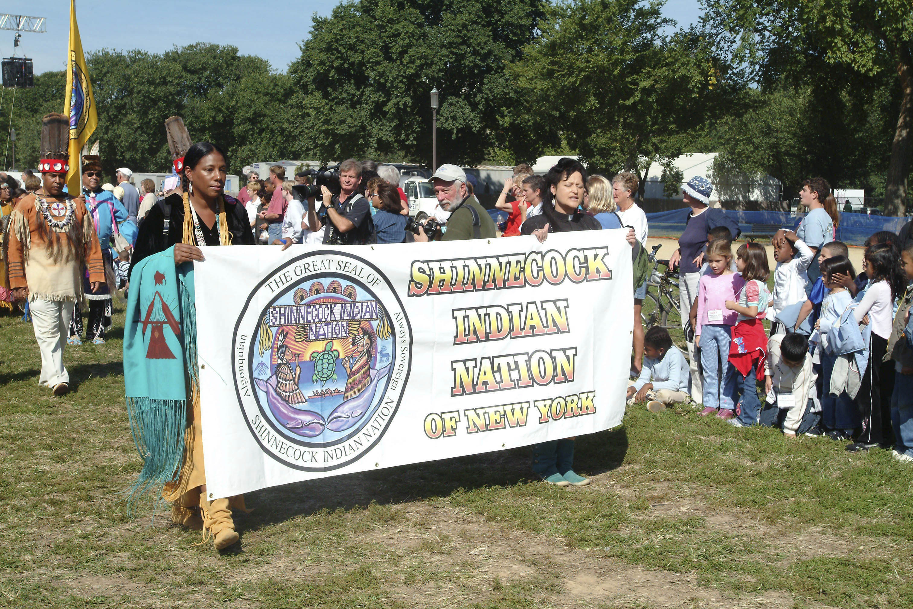 Two women hold up a banner that reads: Shinnecock Indian Nation of New York 