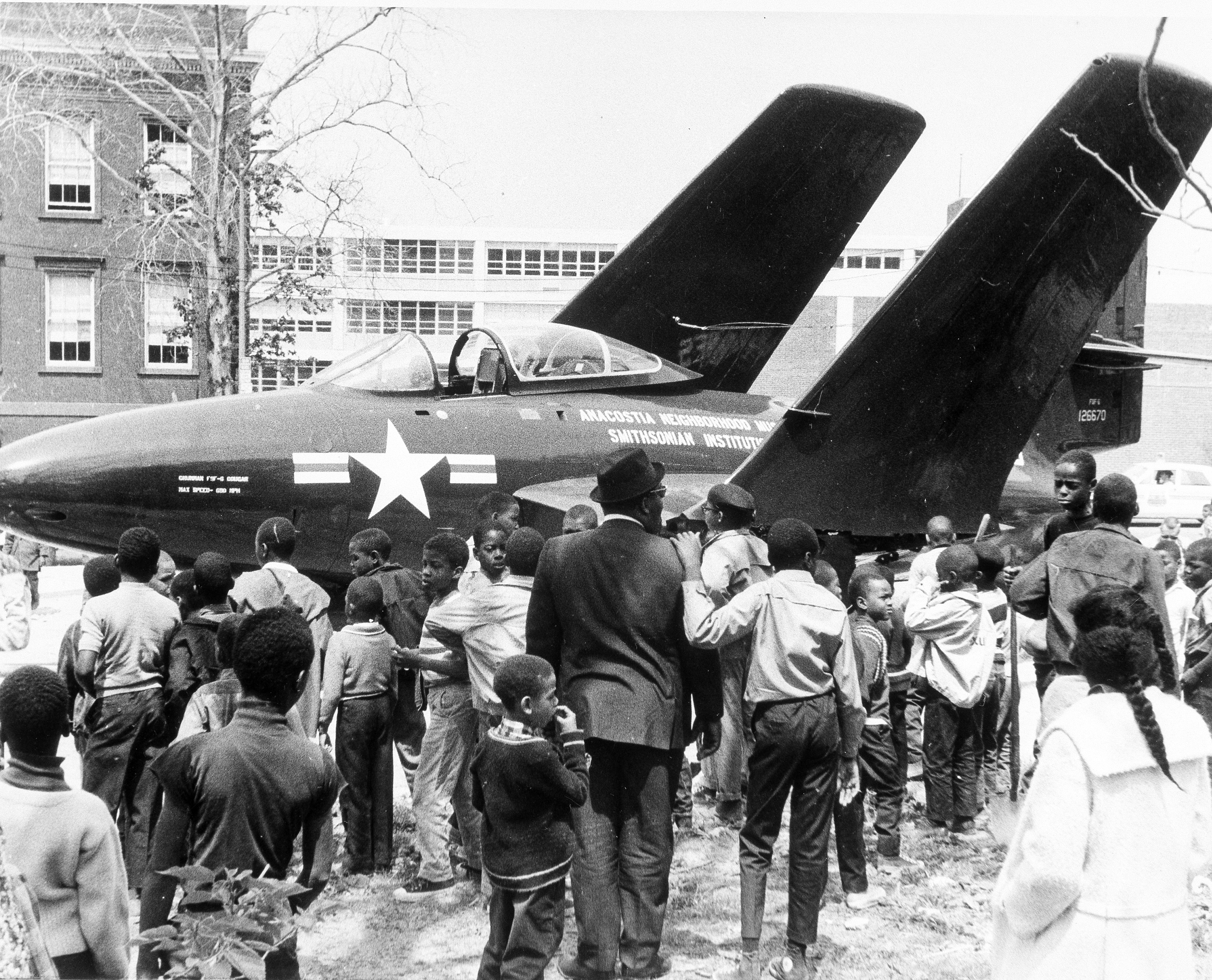Black and white photograph of airplane with crowd around it.