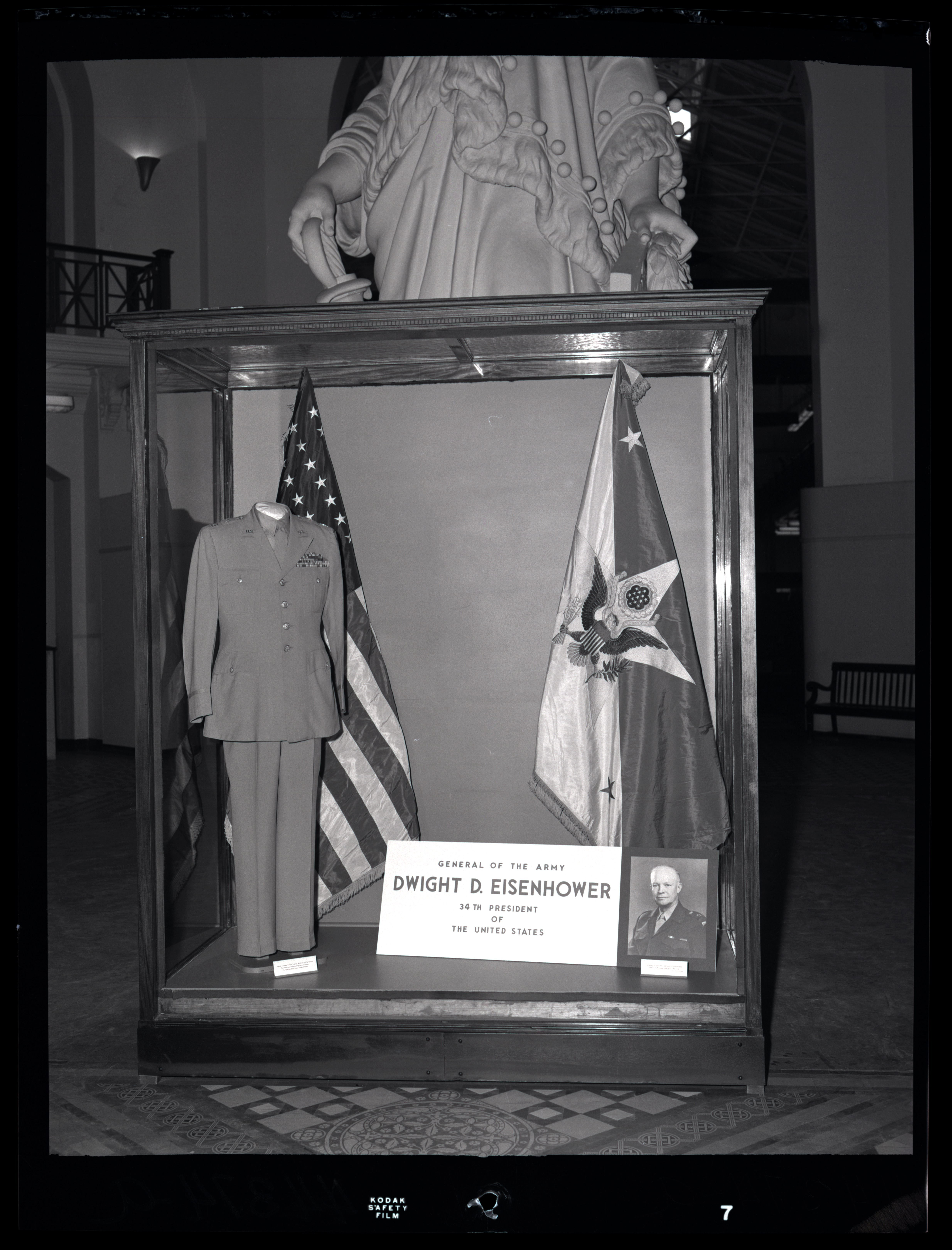 An exhibit case containing two flags and a uniform with a label saying that the uniform belonged to 