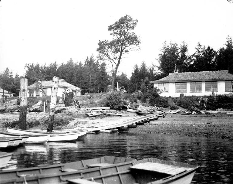 Black-and-white photograph of houses on the edge of a body of water. The cameraperson was on a boat 