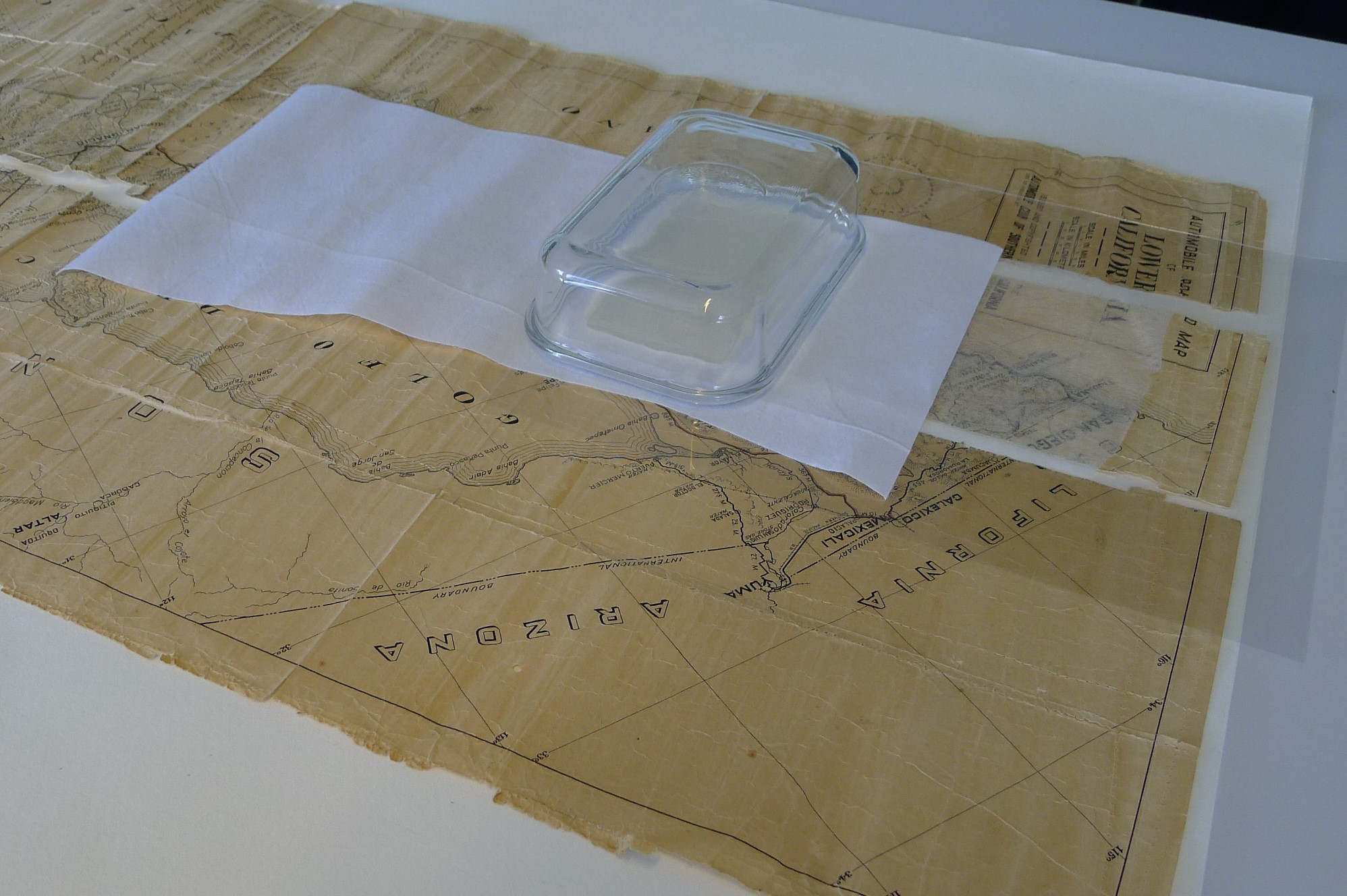 A portion of a printed map sits atop a sheet of Mylar; white Gore-Tex fabric, a transparent yellow-i