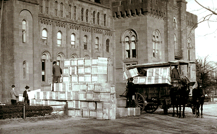 Men loading boxes of box on to a horse-drawn wagon