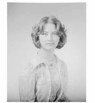 Portrait of a young woman with short, wavy hair. She is looking directly at the camera with a slight smile.