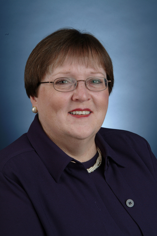 Portrait photograph of a woman with short, brown, red hair and glasses.