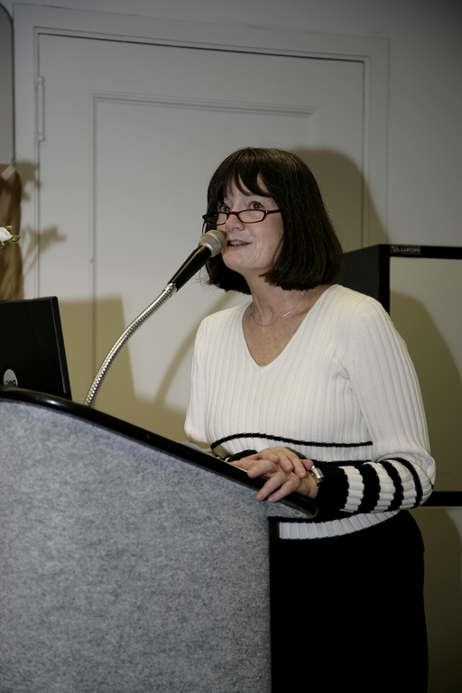 Kaupp stands at a podium. She is speaking into the microphone.