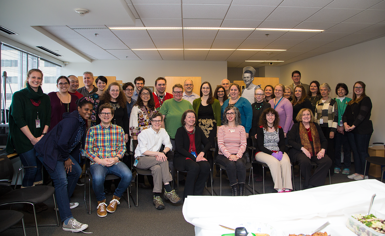 Group photo of people smiling with table filled with food in foreground