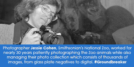 B&W portrait of woman holding camera, leaning against glass with gorilla face on the other side.