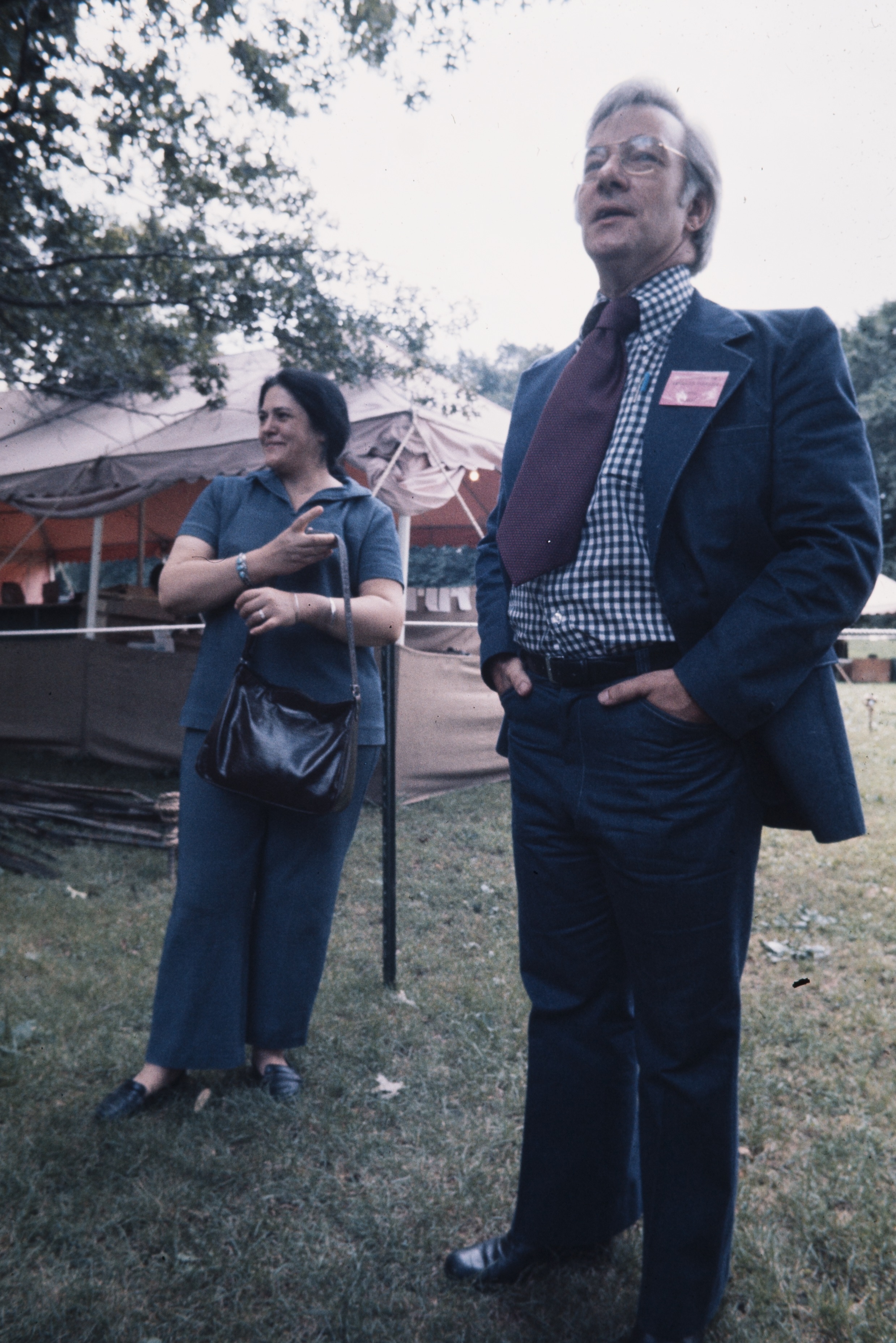 Nahwooksy stands behind a man on the National Mall. A small tent is behind her.