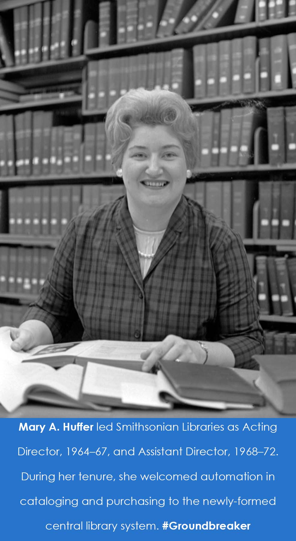 A woman sits at a desk in front of an open book. 