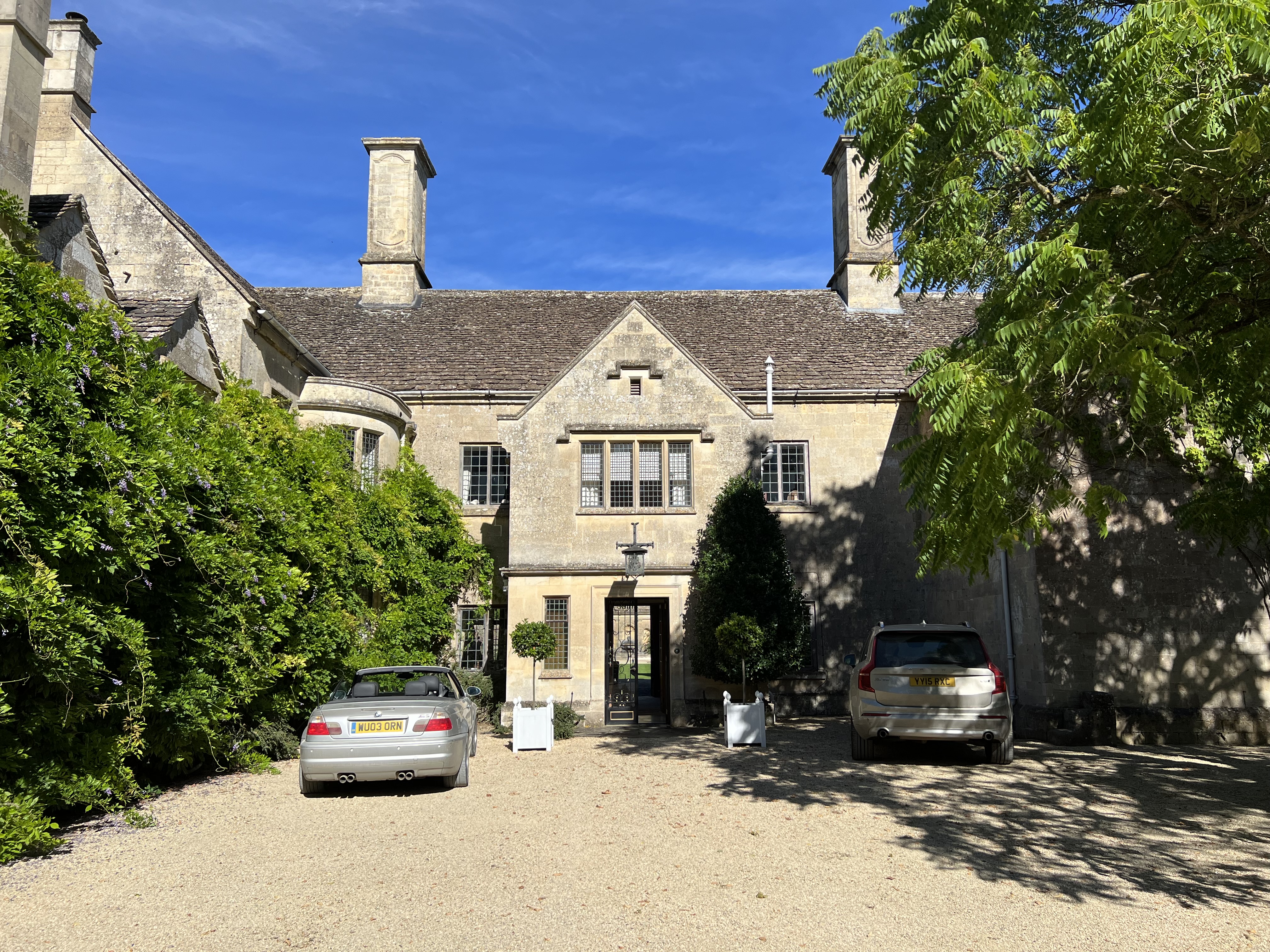 A Georgian stone mansion of classical proportions contrasts with a vibrant blue sky. The left-hand w