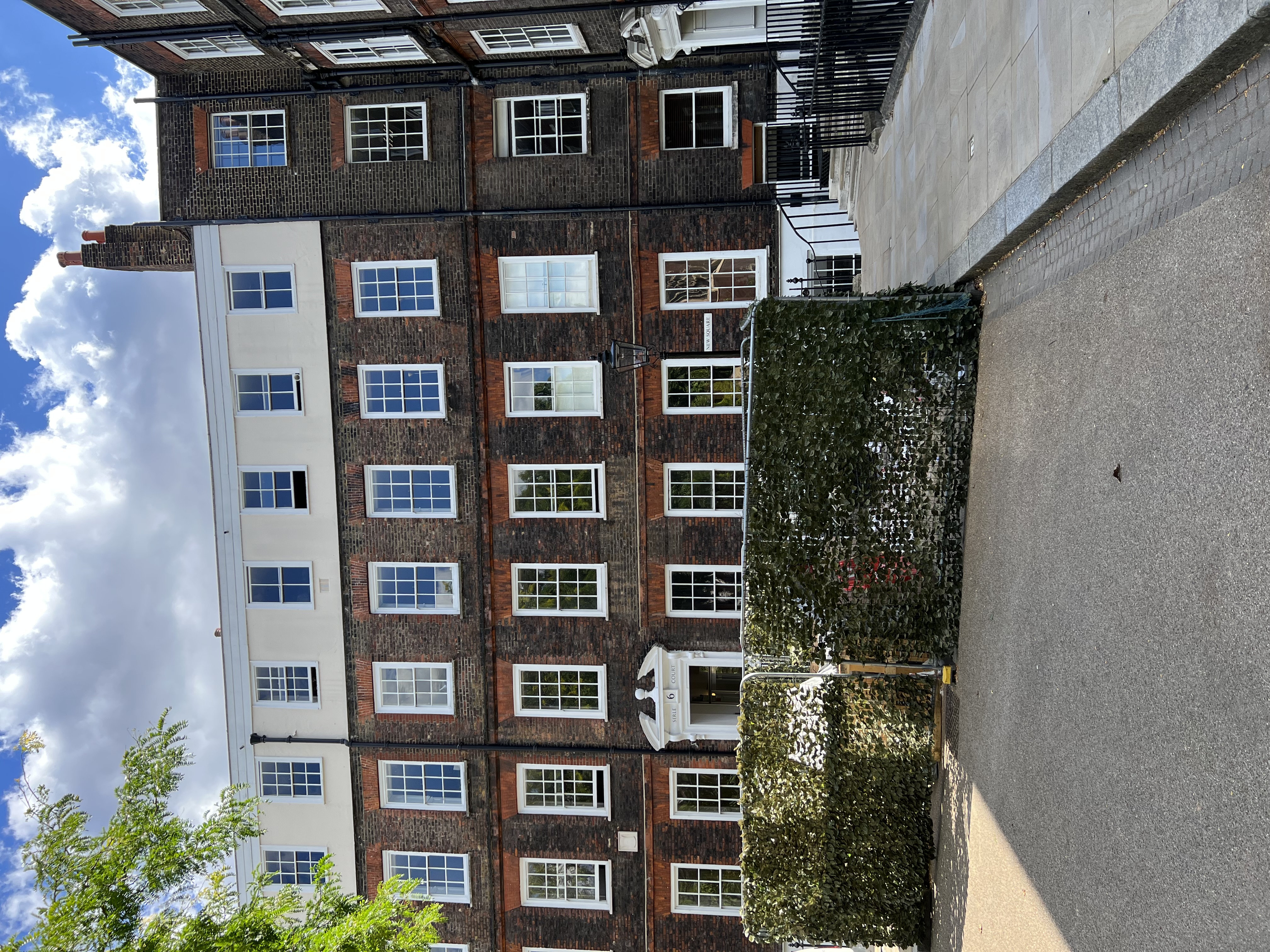 A brick Georgian rowhouse with white sash windows looks onto a London garden square.