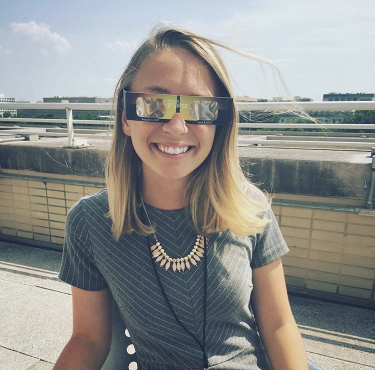 A woman wearing glasses smiles at the camera. 