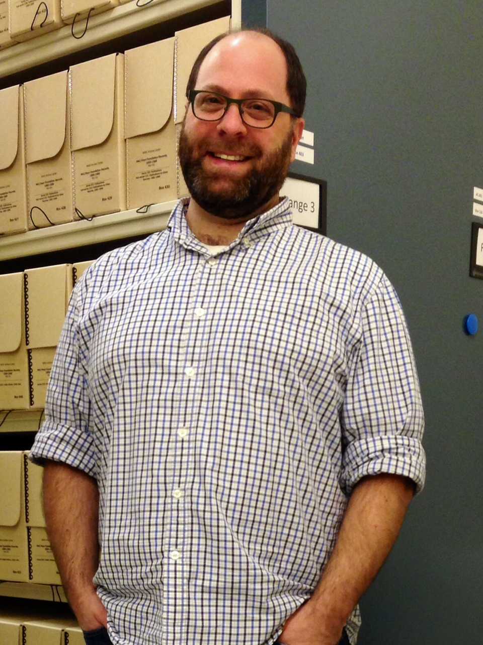 Man posing in front of archival boxes