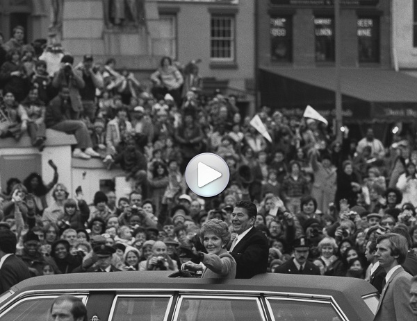 President Ronald Reagan and First Lady Nancy Reagan are in a black limousine and are standing up in 