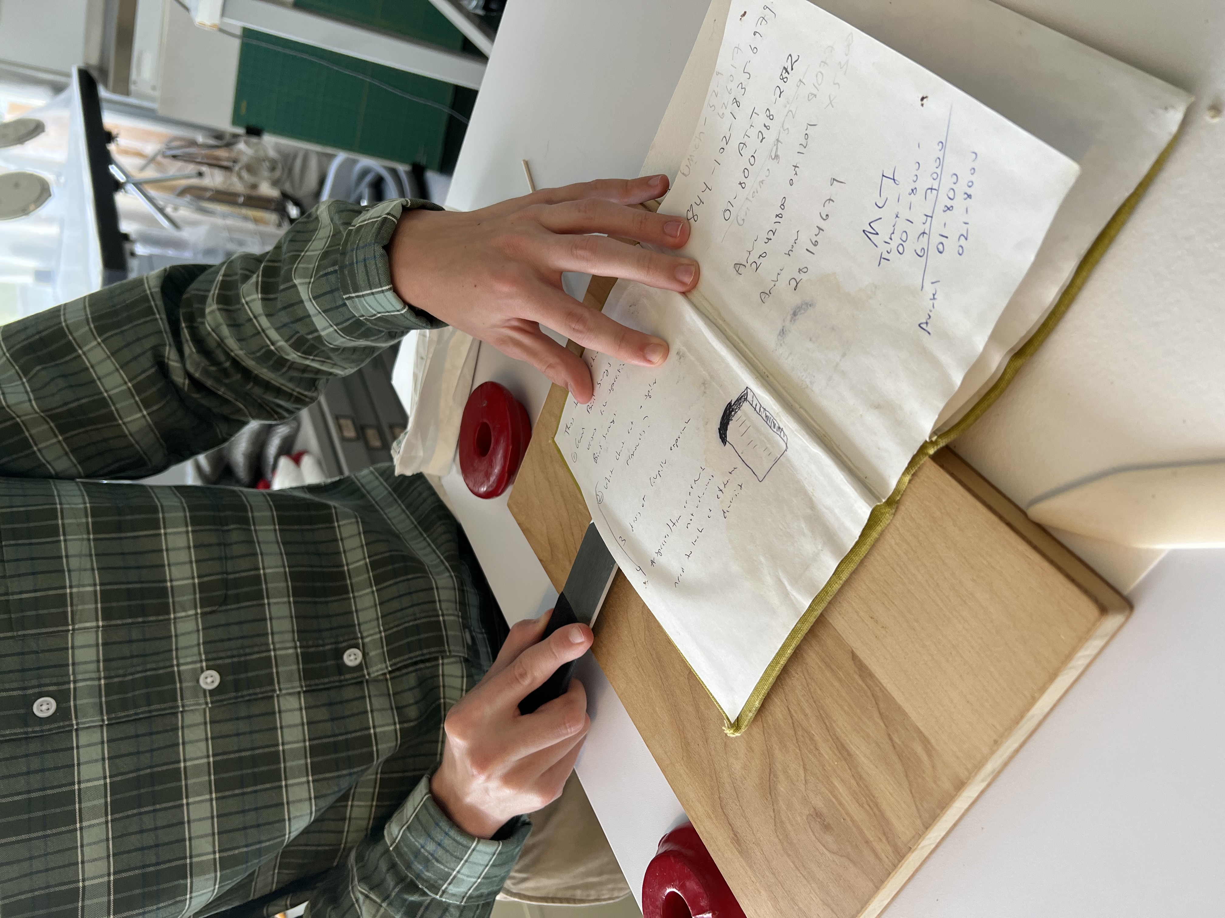 Ben Conklin uses a lifting knife to split the book board and lift the endpaper pastedown from a wate