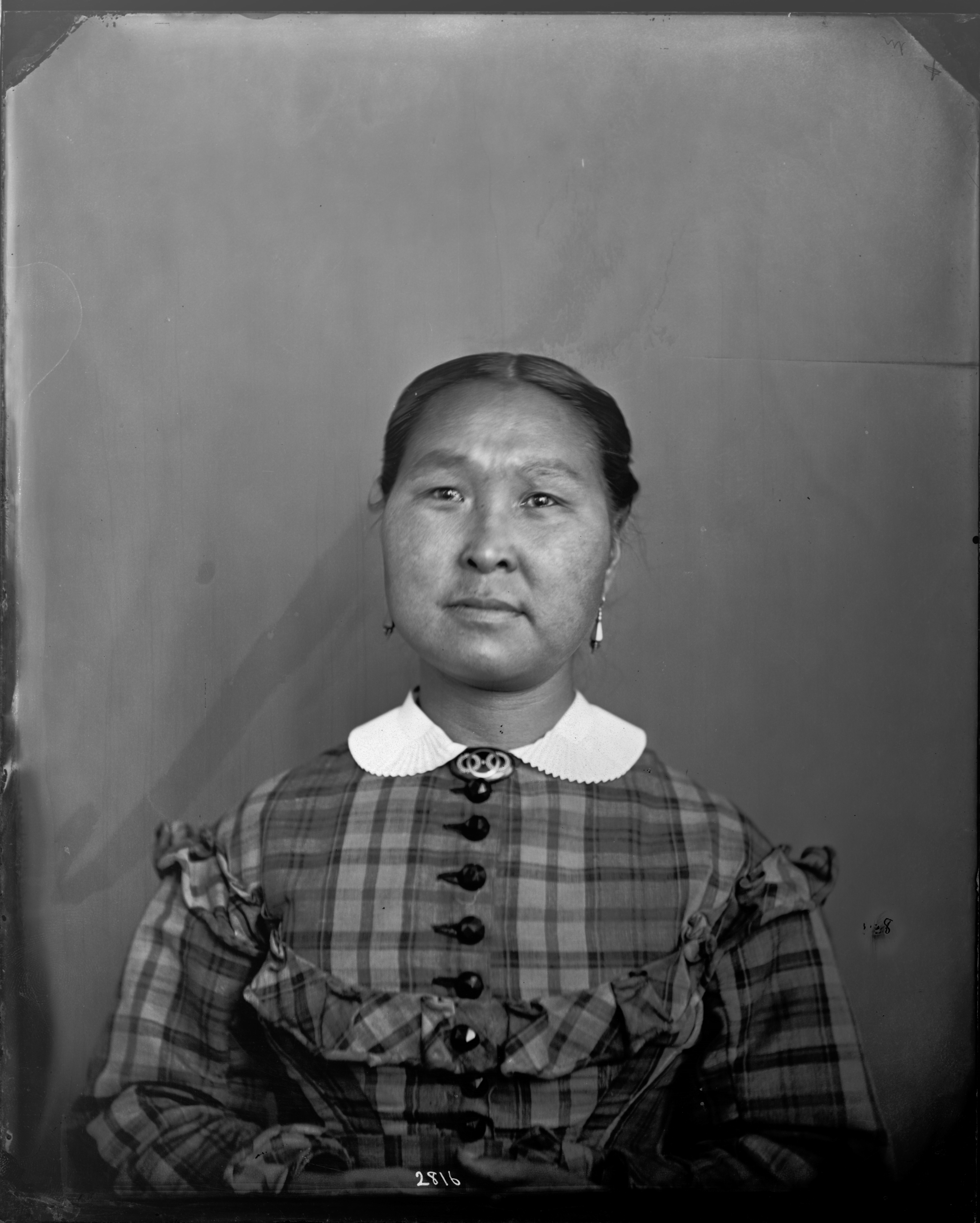 Portrait of Taqulittuq. Her hair is parted in the middle and pulled back into a bun. She is wearing 