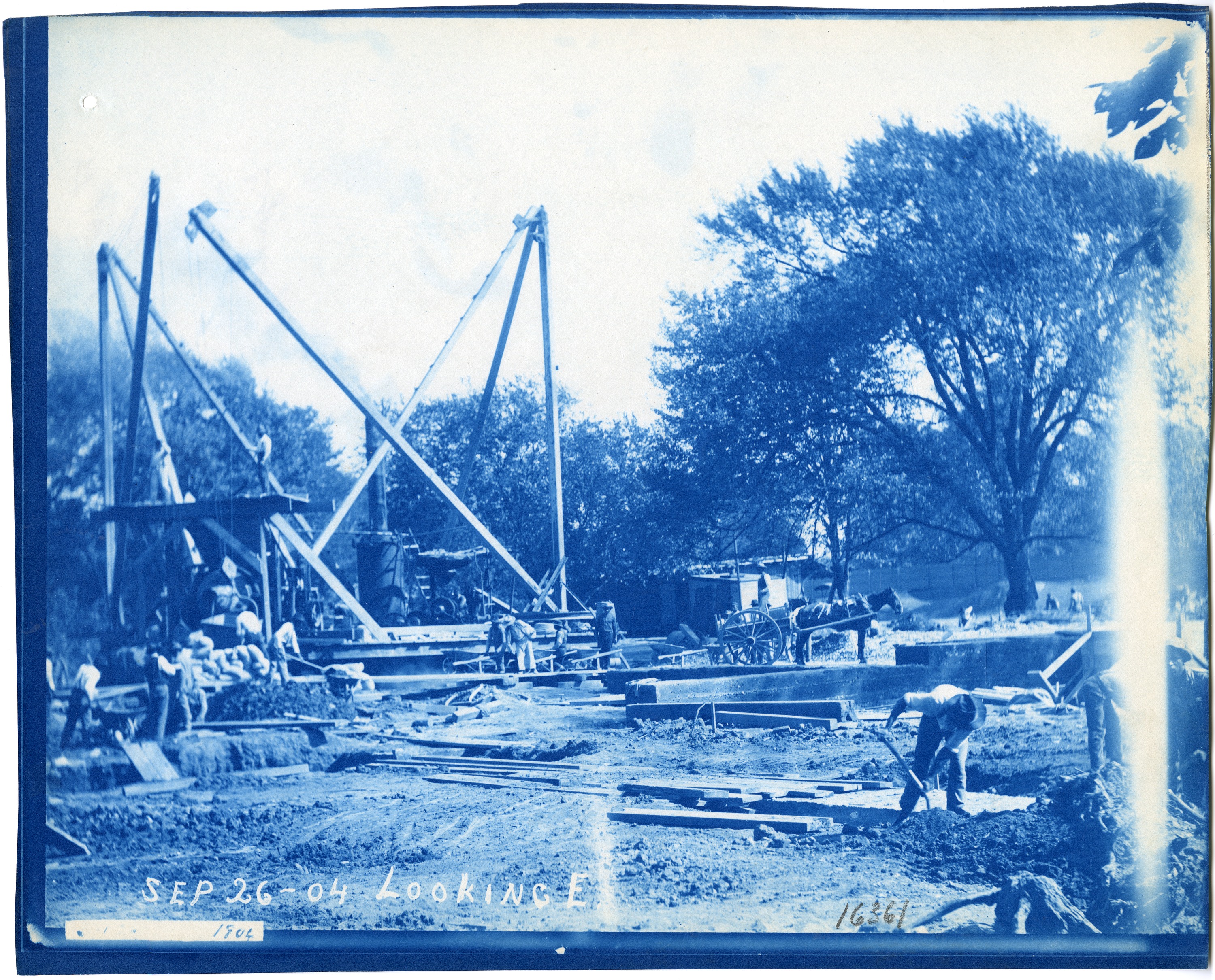 Blue-tinted photograph of people working at a construction site. 