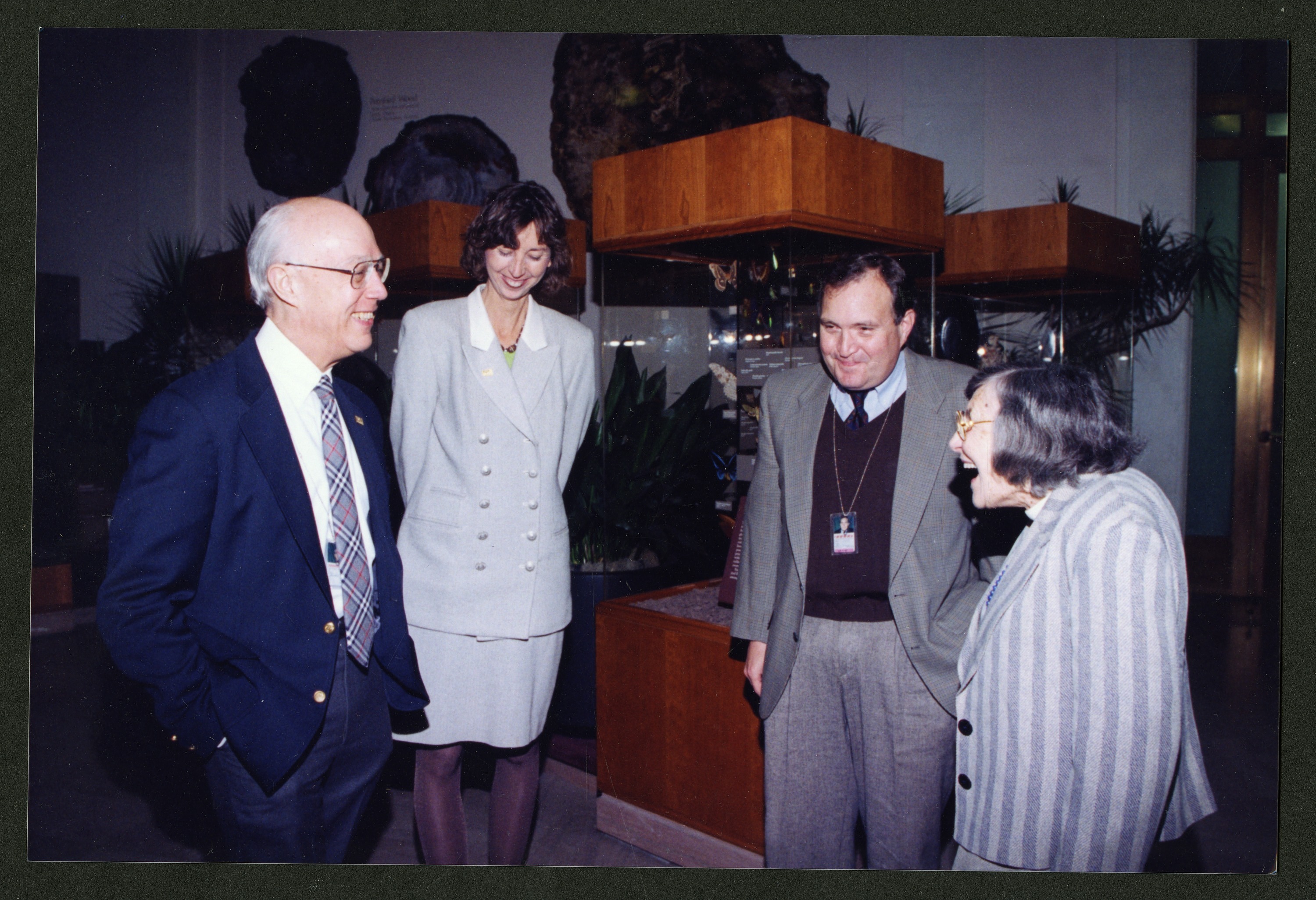 Four people, two men and two women, stand in an exhibit gallery. 