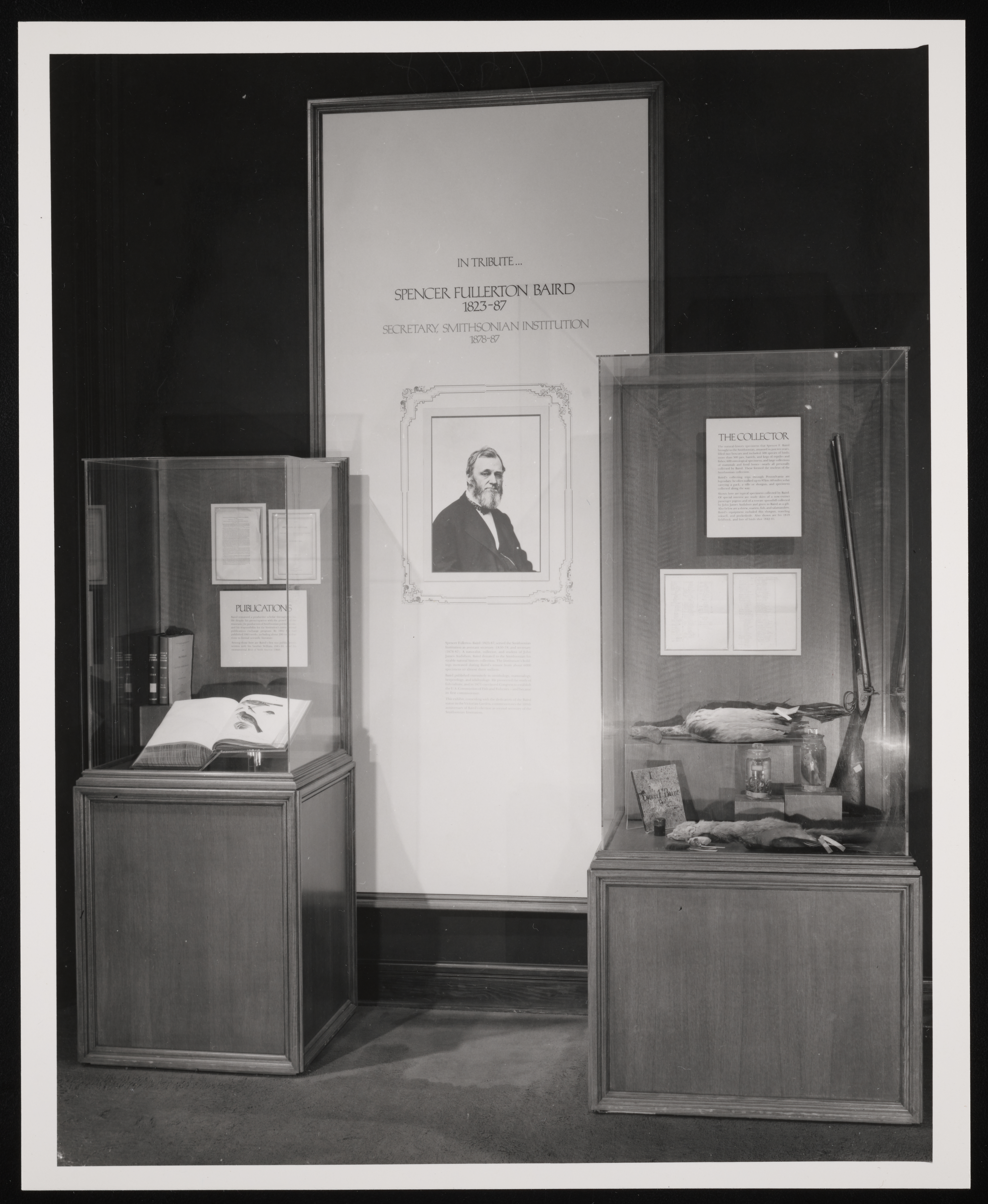 Two exhibit cases on either side of a tall panel that reads: In tribute...Spencer Fullerton Baird 1823-87 Secretary, Smithsonian Institution 1878-87. 