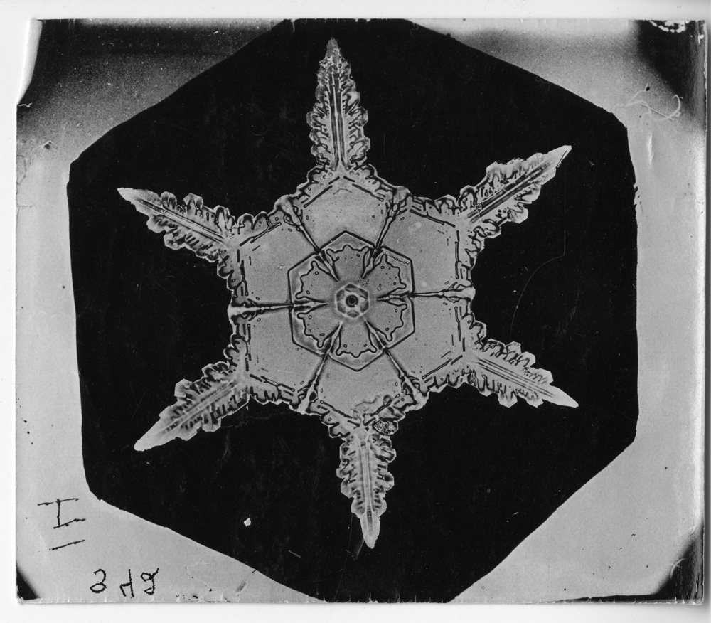 Close-up of a photograph of a snowflake with six points.