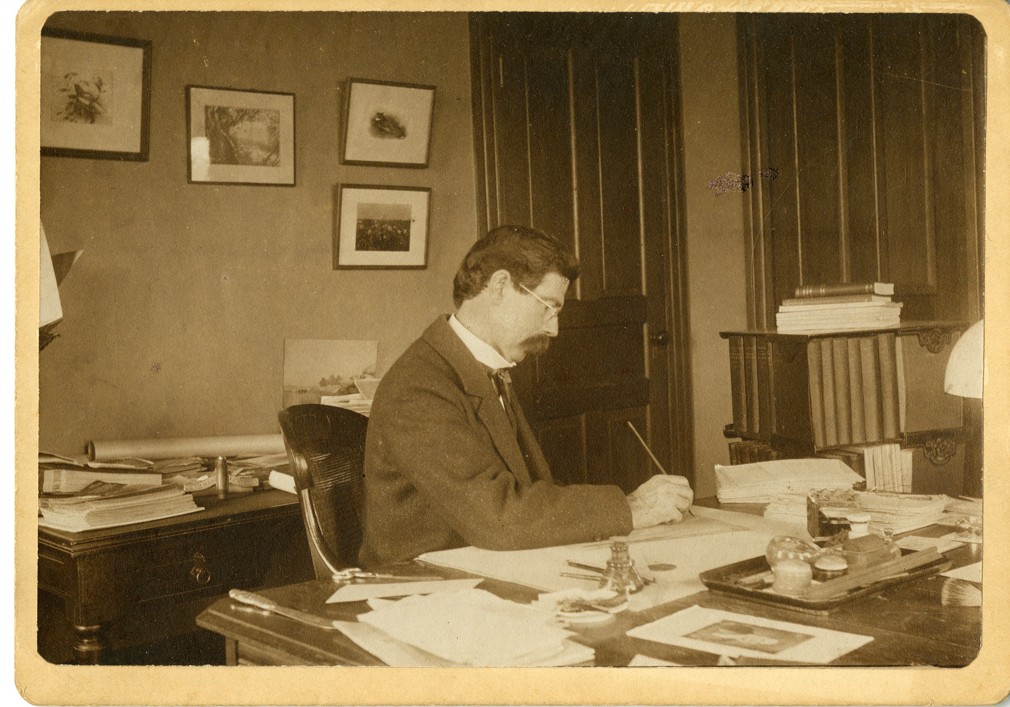 Robert Ridgway sits writing at his desk in his office located in the United States National Museum, 