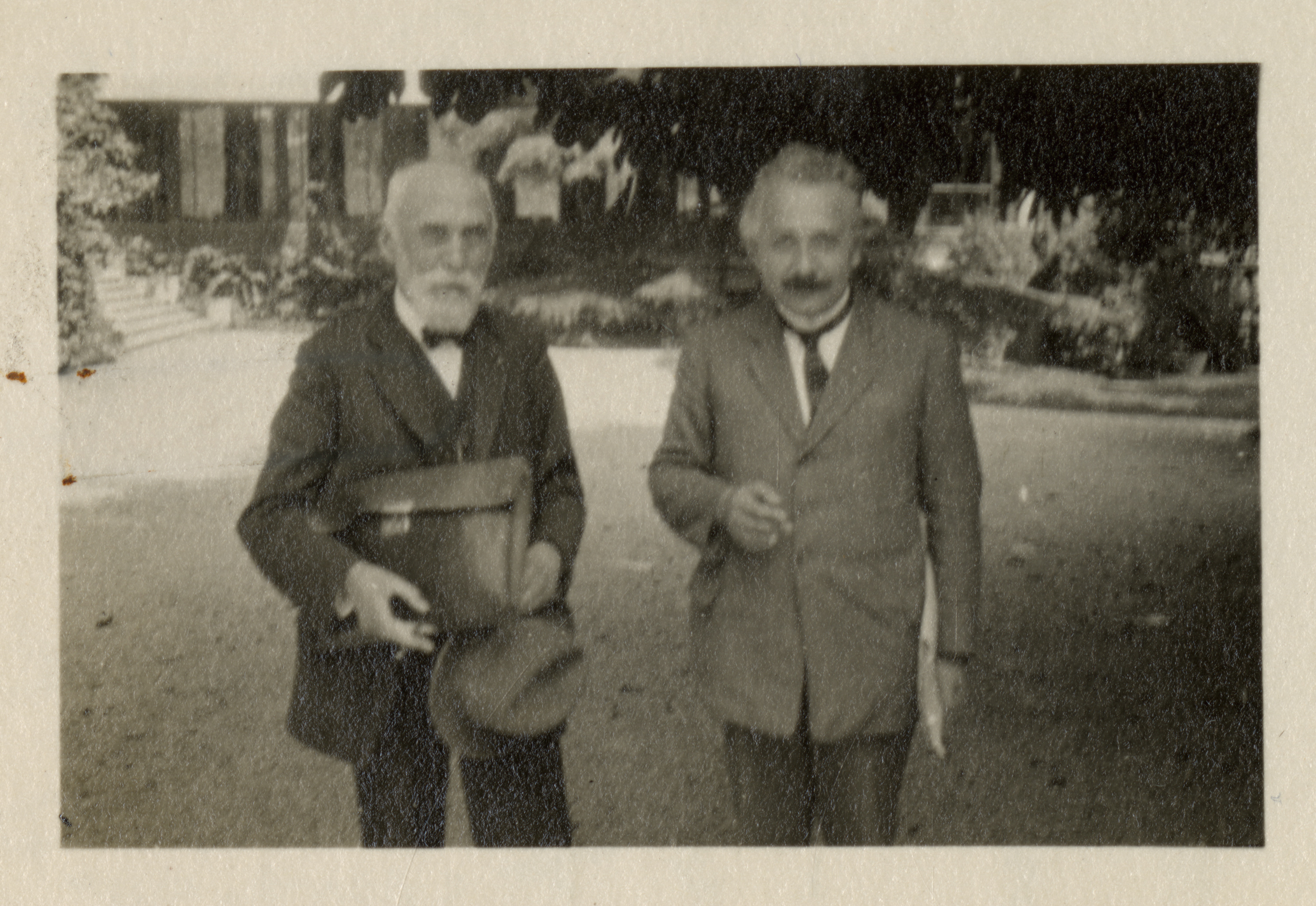 Black and white, slightly out of focus photograph of Lorentz and Einstein standing side by side out doors.