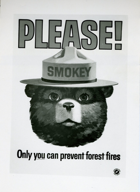 Scan of a black and white forest fire prevention poster featuring the head of Smokey the Bear