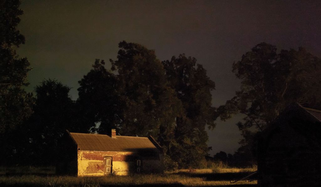 Color photograph of dilapidated house in dark light.