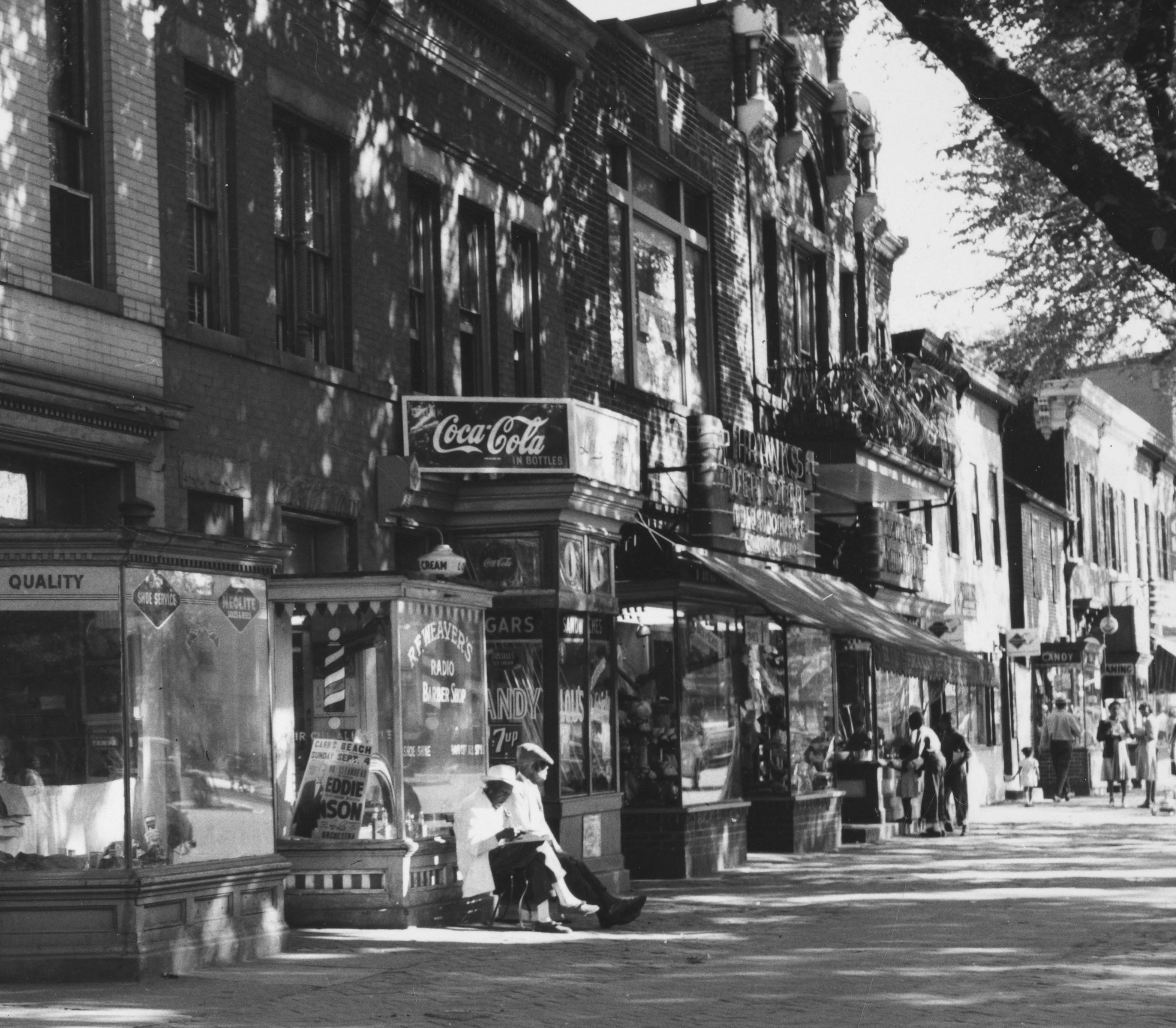 urban street scape with barber shop, candy shop, and African Americans walking the street