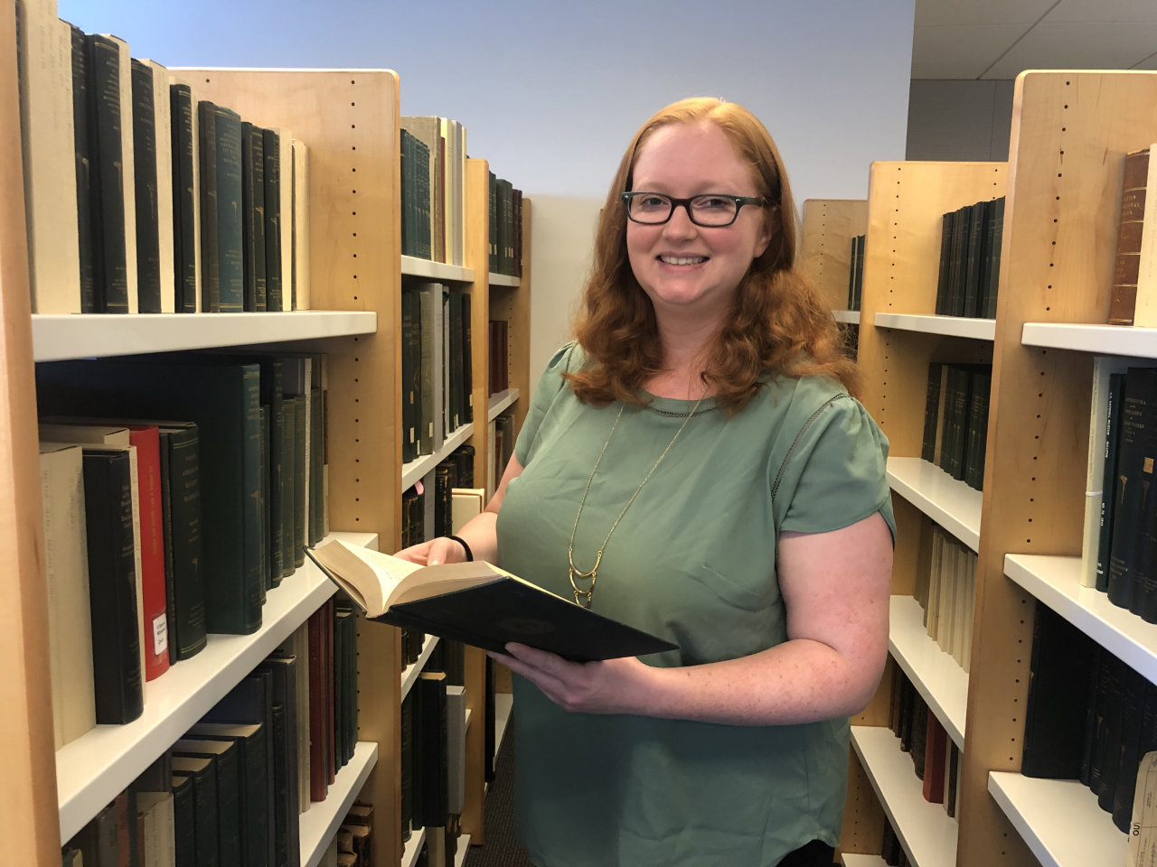 A woman holds open a book in the reading room. 