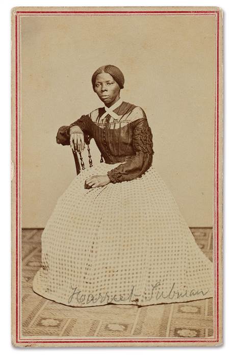 Sepia toned image of African American woman posed and seated in chair. 