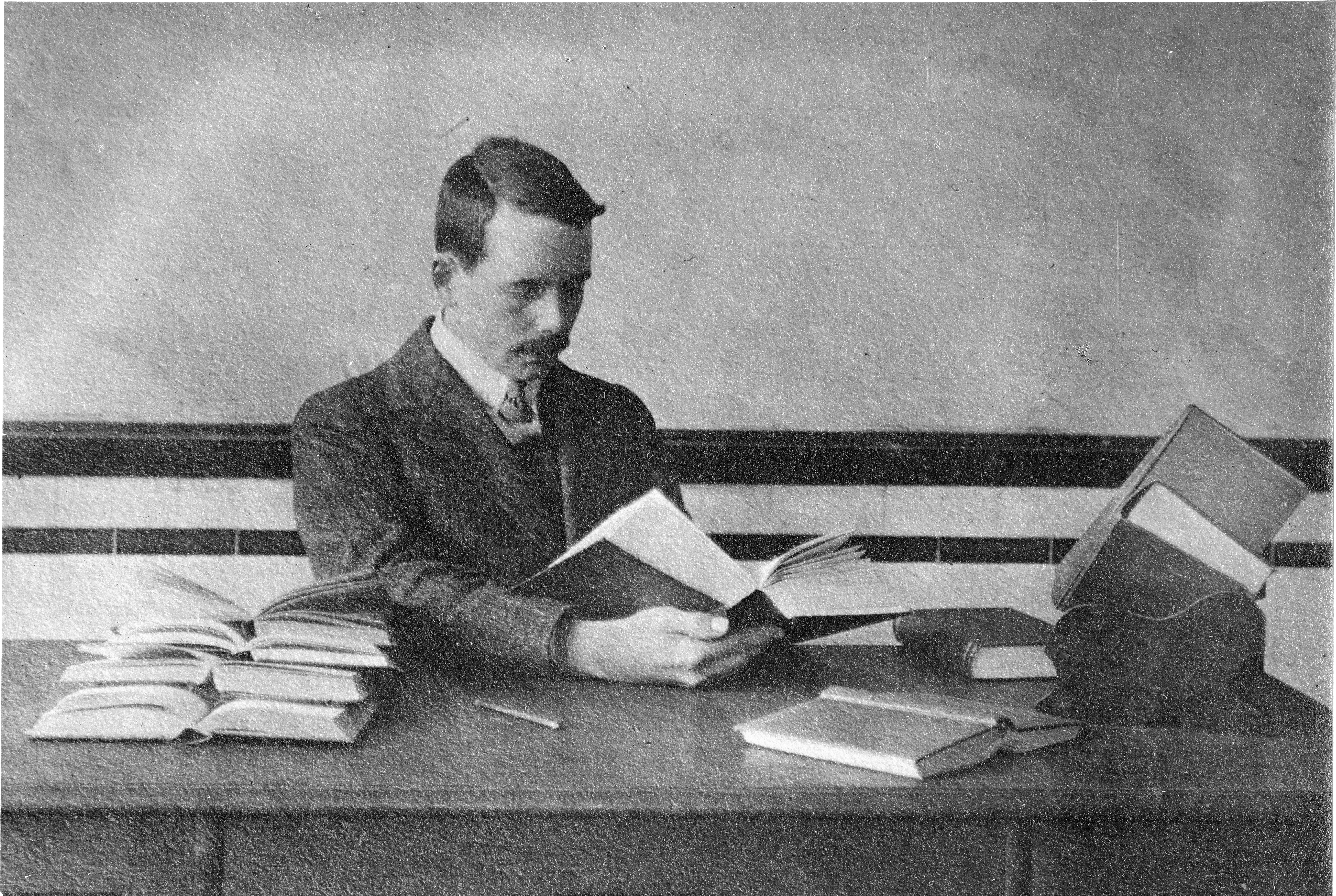 A man sits at a desk with an open book. 