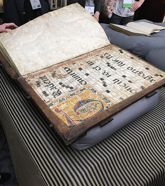 Large book resting on a table. It is open to a page. 