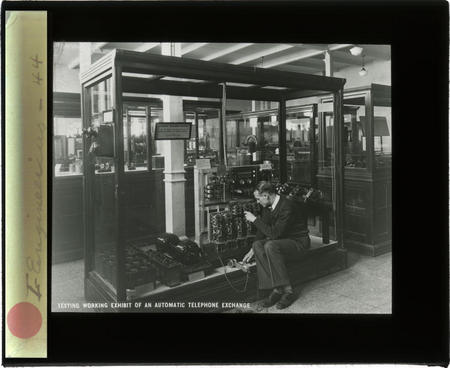 A staff member tests a working exhibit of an automatic telephone exchange.