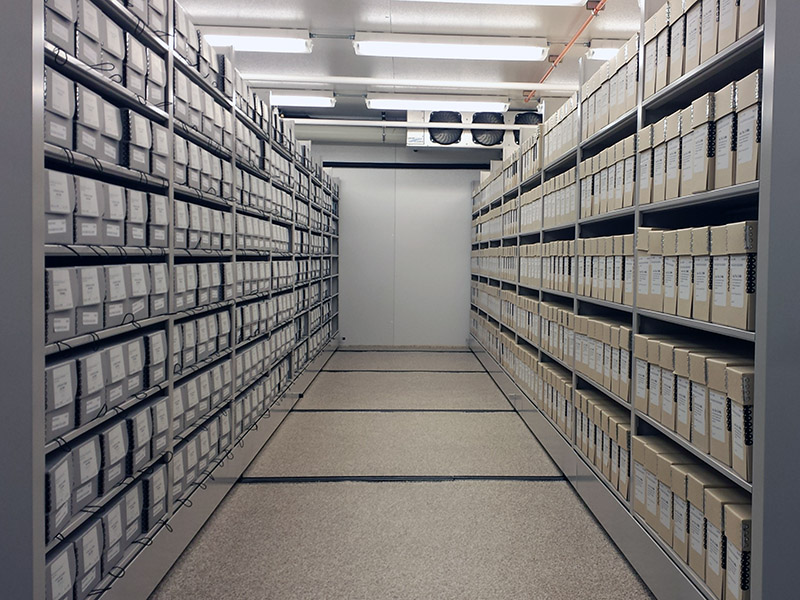 An aisle of metal shelves with archival boxes