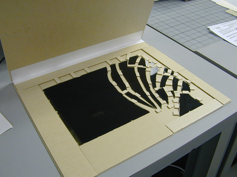 grey folder holding glass negative with buffers between broken pieces