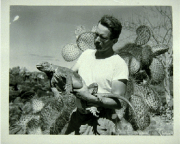 Photo of Schmitt holding an iguana with a cactus in the background 