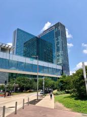 Color image of a tall glass building against and almost completely blue sky.