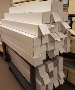 Tall, thin boxes are stacked on a cart in a storage space.