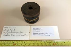 Black circular device with a tape measure and description cards below it.