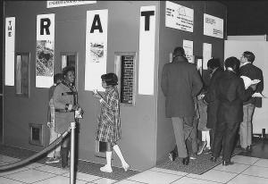 Black and white photograph of both children and adults viewing exhibition.