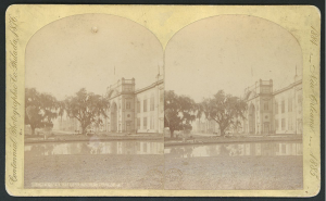 Black and white double photograph of white building with pond in front.