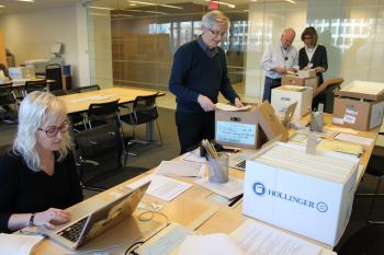 Four volunteers at a long table researching archival records.