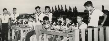 Black and white photograph of a group of boys looking through telescopes.