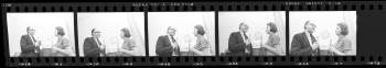 35mm cut black and white negative of Cynthia Helms interviewing Keith E. Melder, both are holding microphones and standing in front of a statue bust.