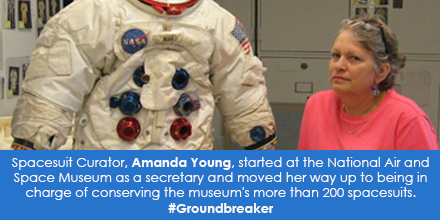 Portrait of smiling woman next to spacesuit.